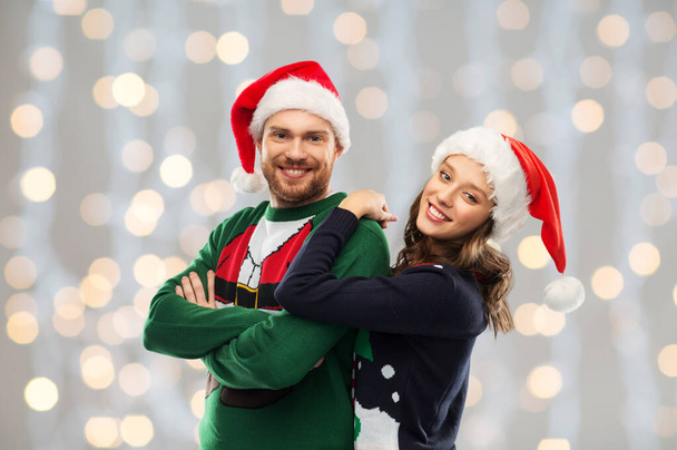 happy couple in christmas sweaters and santa hats - Fotoğraf, Görsel