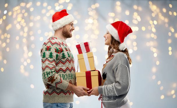 happy couple in christmas sweaters with gifts - Fotografie, Obrázek