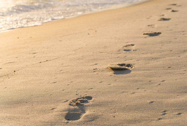 Strandlinie am Meer mit Fußabdrücken im Sand.  - Foto, Bild