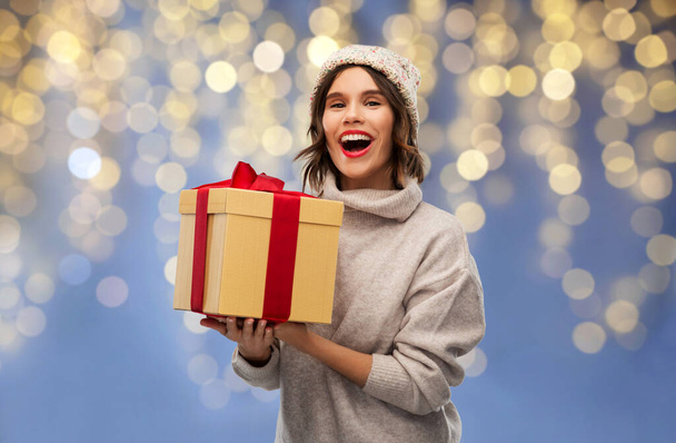 young woman in winter hat holding christmas gift - Фото, изображение
