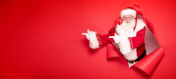 Santa Claus pointing on red empty background. - Фото, изображение