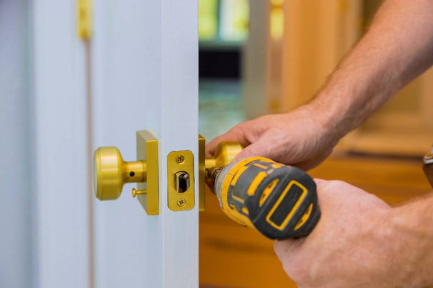 Closeup of a professional locksmith installing or new lock on a house door with screwdriver - Photo, Image