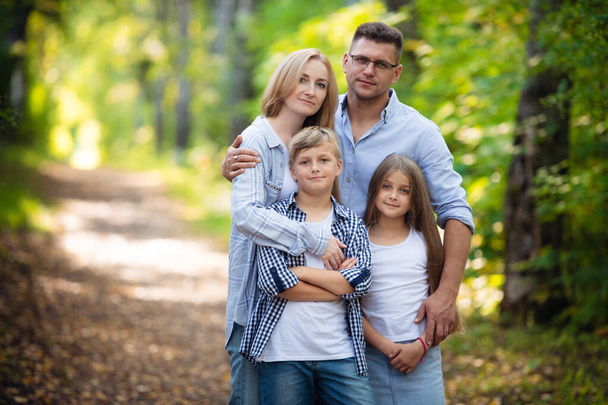 Портрет счастливой семьи из четырех человек в зеленом летнем парке
 - Фото, изображение
