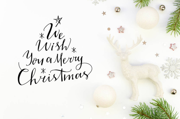 Letras planas con letras We Wish You a Merry Christmas sign texto fondo blanco decorado con decoraciones de Navidad y ramas de abeto. concepto de tarjeta de Navidad
 - Foto, imagen