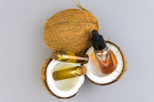 Top view of Half cut coconuts with Coconut essential oils in glass bottles isolated on light grey - Fotó, kép