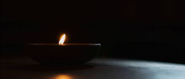 lighting candle in cray cup in dark background - Valokuva, kuva