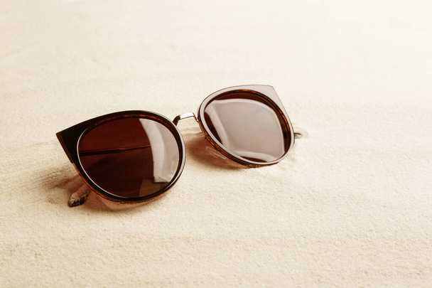 Stylish sunglasses on white sand, space for text. Summer time - Foto, Imagem