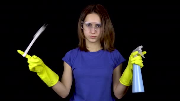 Une jeune femme tord un pinceau de toilette sur son doigt et saupoudre l'eau d'un vaporisateur. Femme dans des lunettes de sécurité et des gants avec des outils pour nettoyer les toilettes. Fille tient une brosse de toilette et de pulvérisation
 - Séquence, vidéo