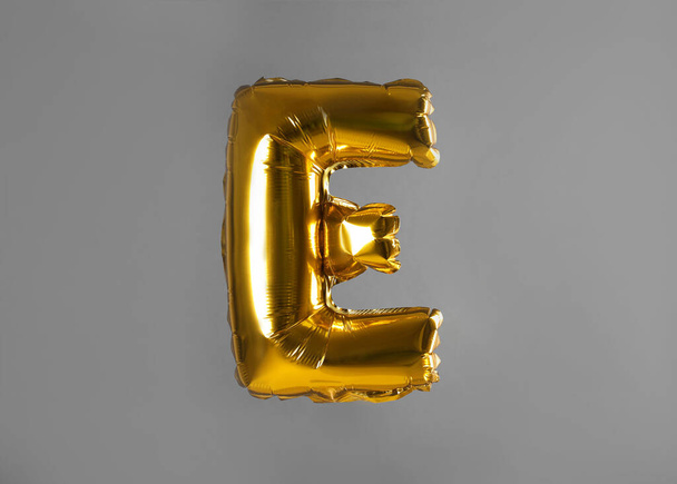 Golden letter E balloon on grey background - 写真・画像
