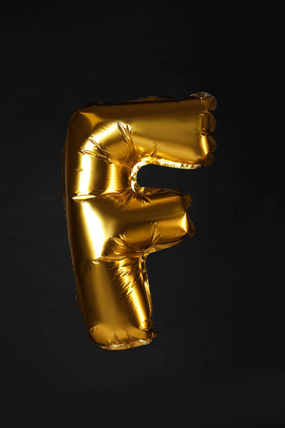 Golden letter F balloon on black background - 写真・画像