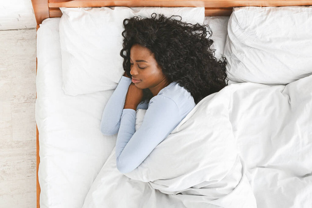 Visão traseira da jovem mulher dormindo em sua cama
 - Foto, Imagem