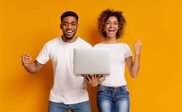 Happy african girl and guy with laptop enjoying good news - Foto, Imagen