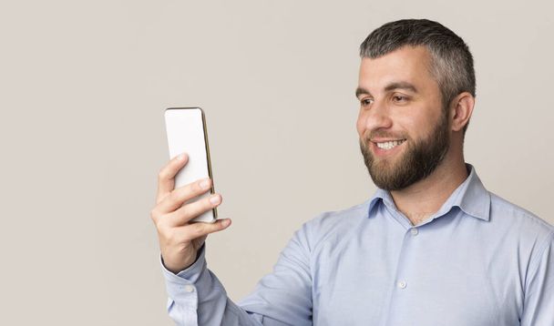 fröhlicher Mann mit Gesichtserkennung auf modernem Smartphone - Foto, Bild