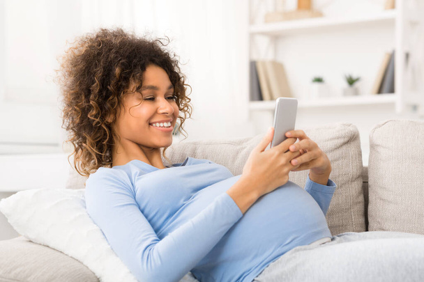 Счастливая беременная женщина в сети на смартфоне
 - Фото, изображение