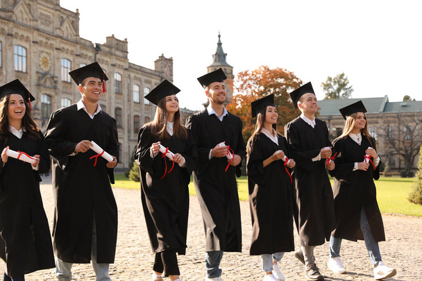 Happy students with diplomas outdoors. Graduation ceremony - Fotoğraf, Görsel