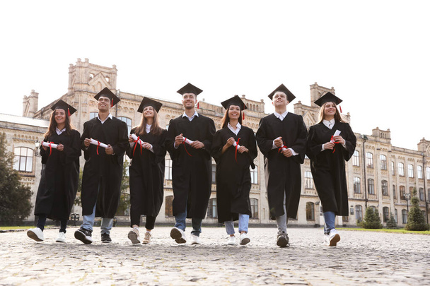 Happy students with diplomas outdoors. Graduation ceremony - Photo, Image