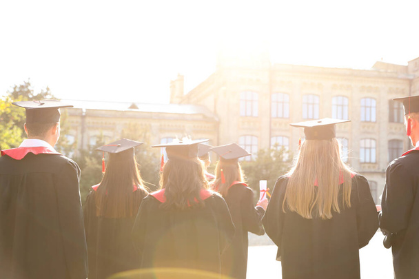 Группа студентов в академических шапках и платьях на открытом воздухе. Выпускная церемония
 - Фото, изображение