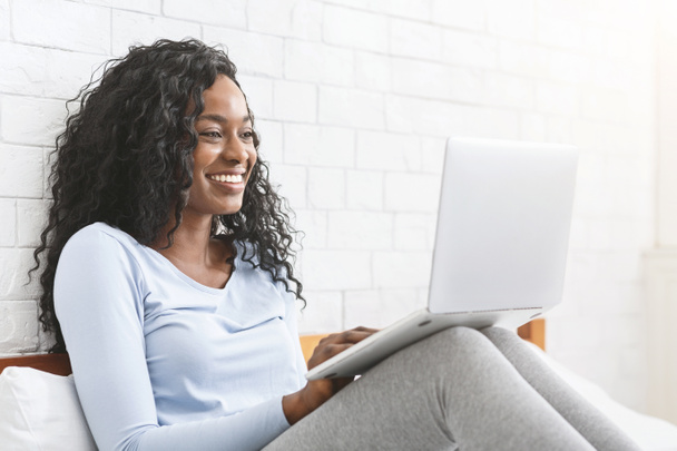 glückliche junge Afro-Lady chattet online im Schlafzimmer - Foto, Bild
