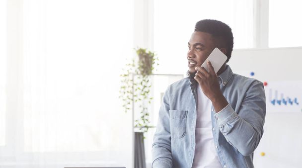 Komea musta työntekijä puhuu matkapuhelimella toimistossa
 - Valokuva, kuva