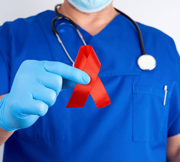 médecin en uniforme bleu et gants en latex stériles tient une côte rouge
 - Photo, image
