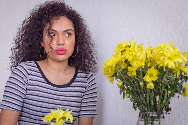 Young woman with curly hair and red lips with yellow flowers - Fotografie, Obrázek