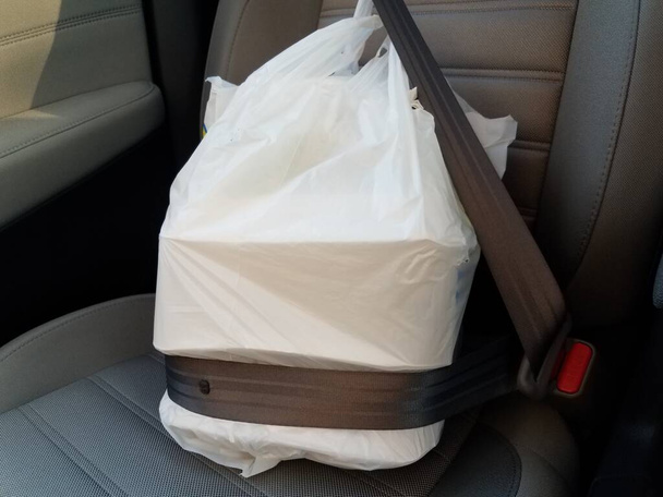 プラスチック製の袋を取り出し配達するか車のシートベルトで食べ物を食べに行きます - 写真・画像