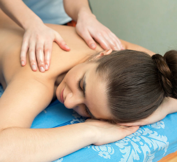 jong meisje liggend op haar buik met massage - Foto, afbeelding
