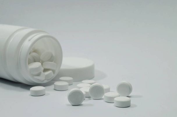 Az aszpirin-paracetamol gyógyszerkapszula segít az antibiotikumok fehér hátterű üvegben való gondozásában. - Fotó, kép