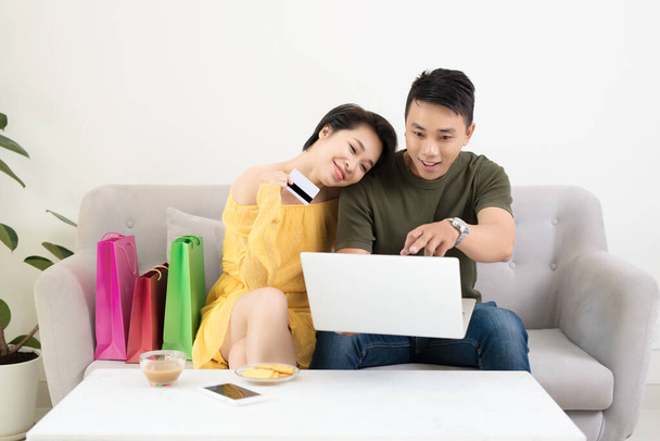 Joven pareja asiática haciendo compras en línea en el ordenador portátil en casa
 - Foto, imagen