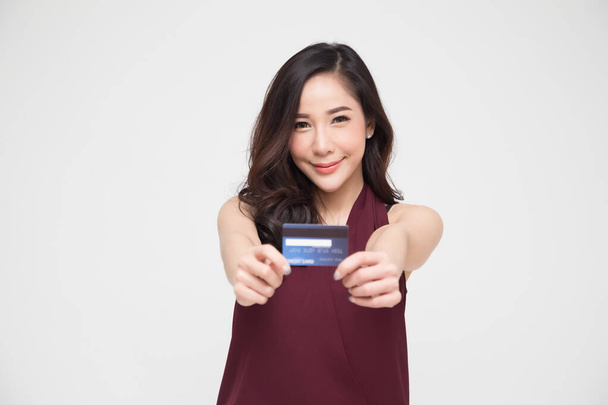 Молодая красивая азиатская женщина улыбается, показывая, представляя кредитную карту для оплаты или оплаты онлайн бизнеса, платить коммерсанта или в качестве аванса наличными для товаров, держатель карты или лицо, которое владеет картой - Фото, изображение