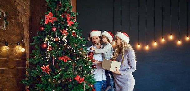 Family decorates the Christmas tree at home in Christmas - Foto, Imagen