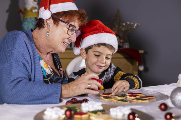Grandmother and grandson decorating cookies on Christmas time - Photo, Image