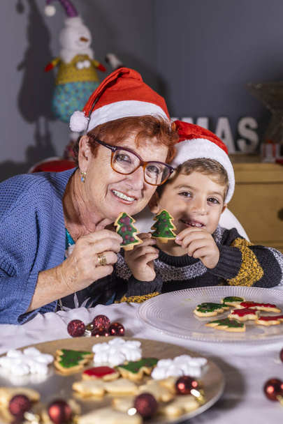 Abuela y nieto mostrando galletas caseras de Navidad
 - Foto, imagen