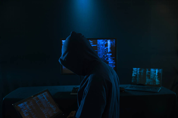 Internet crime concept. Hacker working on a code on dark digital background with digital interface around. - Фото, зображення