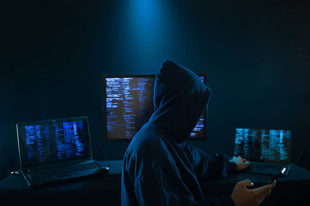 インターネット犯罪の概念。デジタル インターフェイス周りの暗いデジタル背景にコードに取り組んでいるハッカー. - 写真・画像