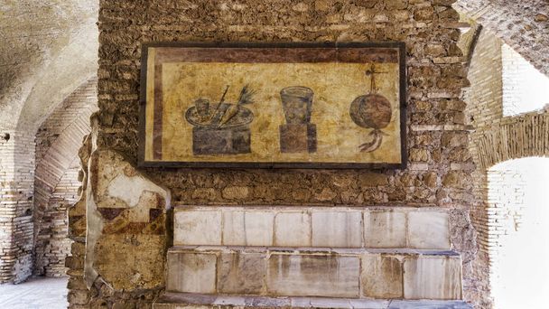 Romeinse rijk archeologische opgravingen in Ostia Antica met het interieur van de Termopolio s woning en de marmeren plank overdekt met decoratieve stilleven fresco 's - Foto, afbeelding
