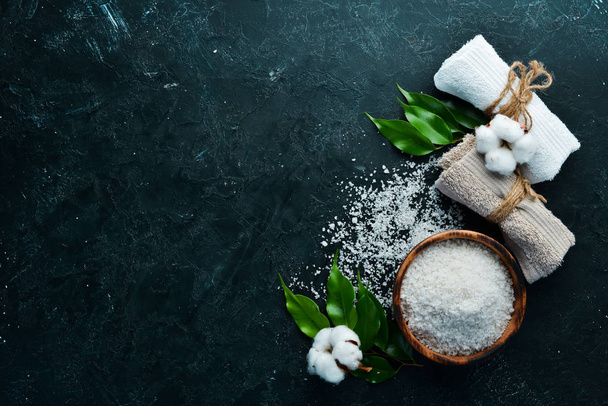 Spa. Sea salt and cosmetic towels. On a black stone background. Top view. Free space for your text. - Foto, imagen