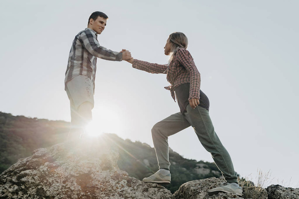 Un jeune randonneur aide sa copine à escalader un rocher pendant une vacatio
 - Photo, image