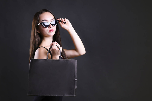 Young beautiful woman with paper bag on dark background. - Foto, afbeelding
