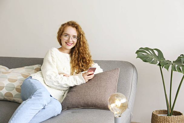 Kręcone włosy brunetka kobieta relaks na kanapie w domu. - Zdjęcie, obraz