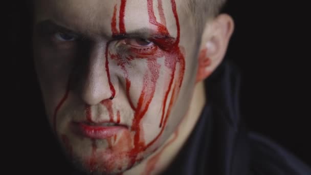 Portret mężczyzny z Halloween. Facet z kapającą krwią na twarzy. Przerażający makijaż. - Materiał filmowy, wideo