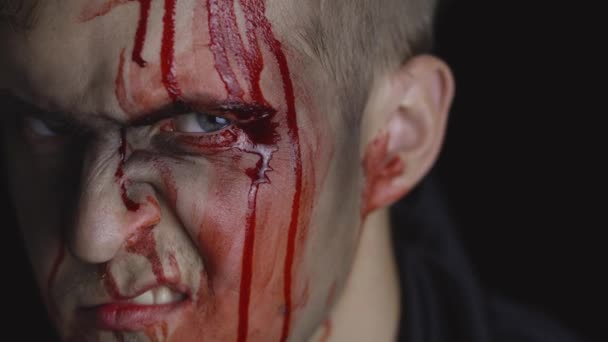 Αποκριάτικο πορτρέτο. Ένας τύπος με αίμα που στάζει στο πρόσωπό του. Τρομακτικό μακιγιάζ - Πλάνα, βίντεο
