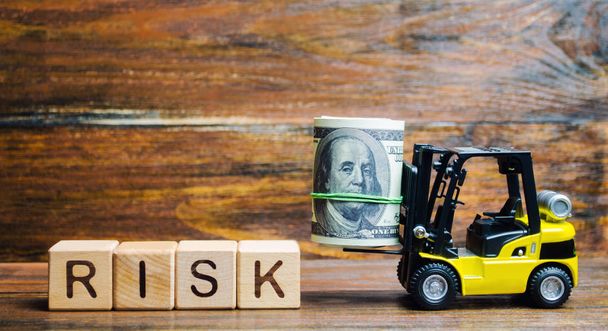 Wooden blocks with the word Risk, money and a forklift. Financial and commercial risk concept. Investing in a business. Risks assessment and management. Credit, loan. Business plan development - Фото, зображення