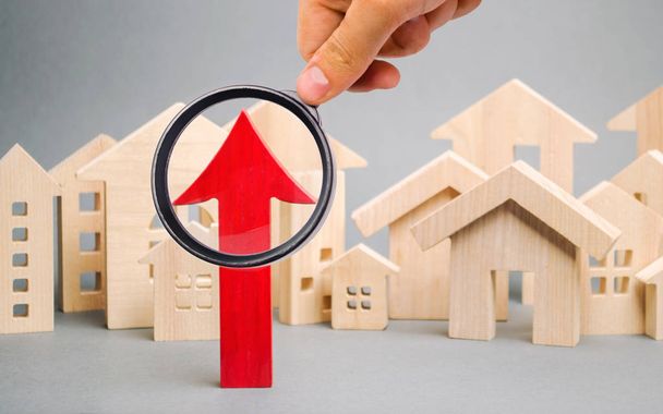 Red arrow up and miniature wooden houses. The concept of rising property prices. High mortgage rates. Expensive rental apartment. Growing demand for home purchase. Population growth in the city. - Foto, Imagem