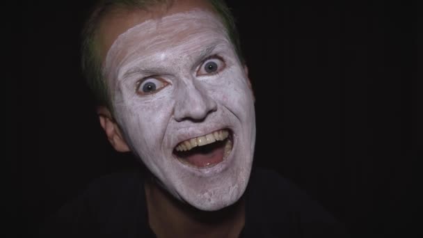Bohóc Halloween férfi portré. Közelkép egy gonosz bohóc arcáról. Fehér arc smink - Felvétel, videó