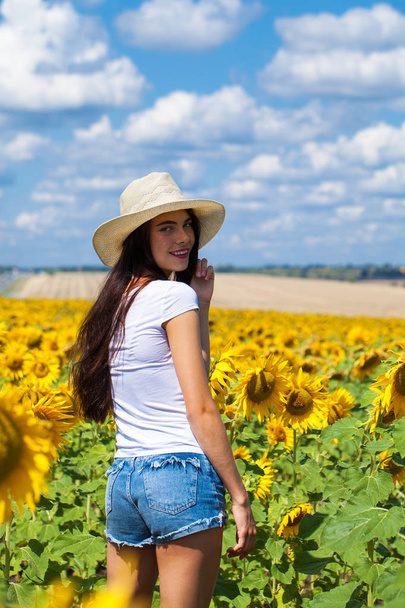 Portrait of a young beautiful girl in a field of sunflowers - Φωτογραφία, εικόνα