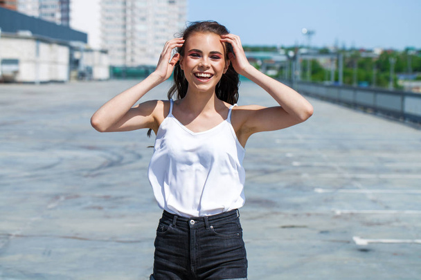 Pretty young brunette model in white summer blouse and jeans, su - Foto, Bild