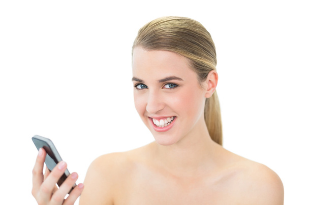 Smiling attractive blonde holding her smartphone - Foto, imagen