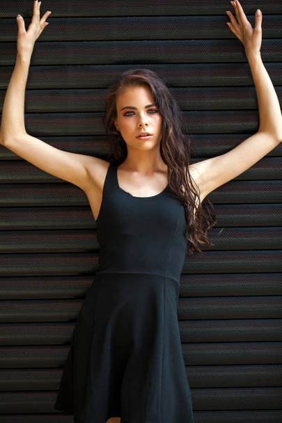 Brunette young woman in sexy Black dress, studio wall indoor - Photo, Image