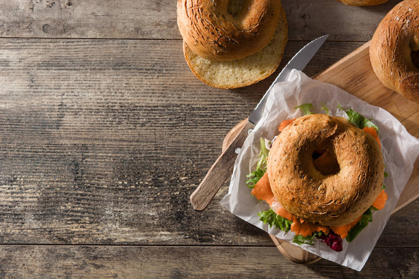 Krem peynirli bagel sandviç, füme somon ve ahşap masada sebze. Üst Manzara. Boşluğu kopyala - Fotoğraf, Görsel